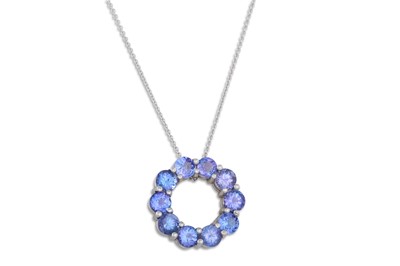 Lot 311 - A CIRCULAR TANZANITE PENDANT, mounted in 14ct...