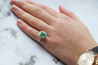 Lot 112 - AN EMERALD AND DIAMOND CLUSTER RING, mounted...