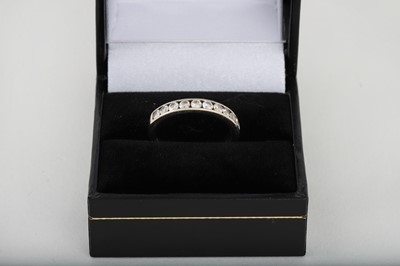 Lot 175 - A DIAMOND HALF ETERNITY RING, channel set in...