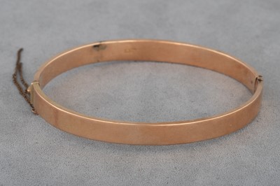 Lot 75 - AN ANTIQUE 15CT GOLD HINGED BANGLE, engraved...