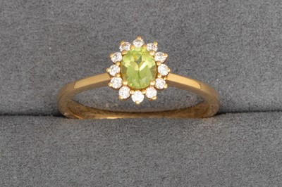 Lot 89 - A PERIDOT AND DIAMOND CLUSTER RING, the oval...