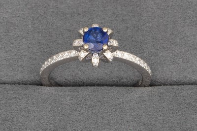 Lot 106 - A SAPPHIRE AND DIAMOND RING, the central round...