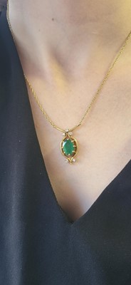 Lot 42 - AN EMERALD AND DIAMOND PENDANT, the oval cut...