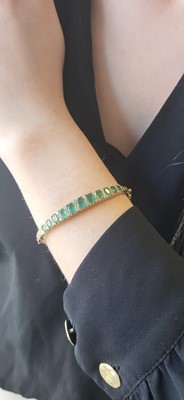 Lot 118 - AN EMERALD AND DIAMOND BANGLE, mounted in...