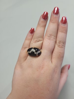 Lot 63 - AN ONYX AND DIAMOND BOMBE RING, mounted in...