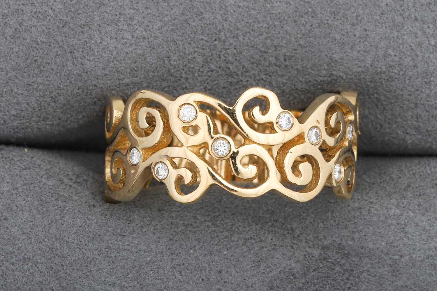 Lot 99 - A DIAMOND SET BAND RING, of scrolled design,...