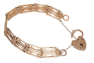 Lot 16 - AN EARLY 20TH CENTURY 9CT GOLD GATE BRACELET,...