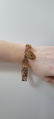 Lot 16 - AN EARLY 20TH CENTURY 9CT GOLD GATE BRACELET,...