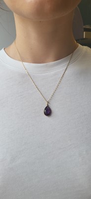 Lot 21 - AN AMETHYST PENDANT, the bezel set mixed cut...