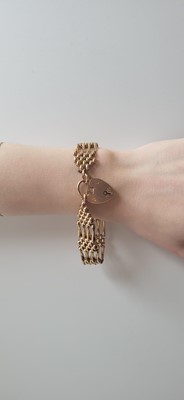 Lot 79 - AN ANTIQUE 9CT GOLD GATE BRACELET, with...