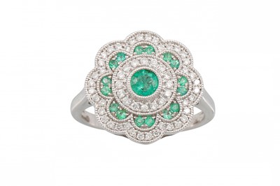 Lot 127 - A DIAMOND AND EMERALD CLUSTER RING, of floral...