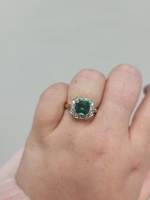 Lot 180 - AN EMERALD AND DIAMOND CLUSTER RING, the trap...
