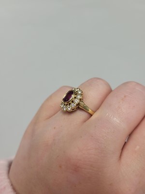 Lot 130 - A RUBY AND DIAMOND CLUSTER RING, the oval ruby...
