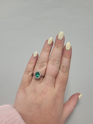 Lot 133 - AN EMERALD AND DIAMOND CLUSTER RING, the oval...