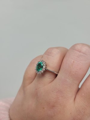 Lot 133 - AN EMERALD AND DIAMOND CLUSTER RING, the oval...