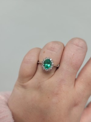Lot 133 - AN EMERALD AND DIAMOND CLUSTER RING, the oval...