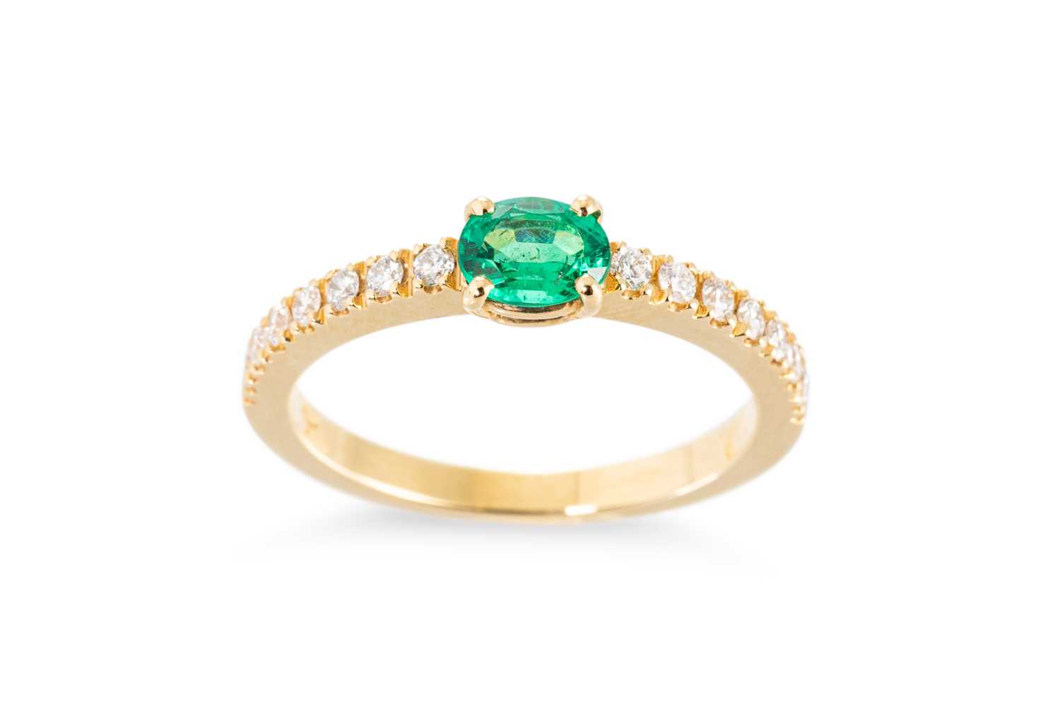 Lot 61 - AN EMERALD AND DIAMOND SET BAND RING, the oval...