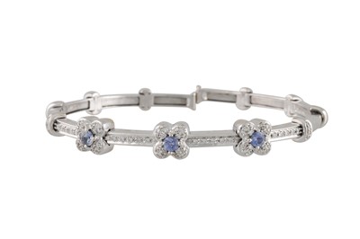 Lot 103 - A DIAMOND AND SAPPHIRE CLUSTER BANGLE, the...