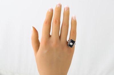 Lot 366 - AN ONYX AND DIAMOND PLAQUE RING, in a white...