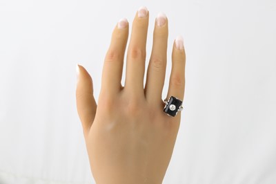 Lot 272 - AN ONYX AND DIAMOND PLAQUE RING, in a white...